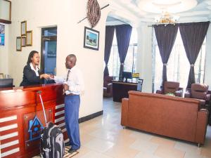 two men standing at a reception desk in a room at Best Point Hotel in Dar es Salaam