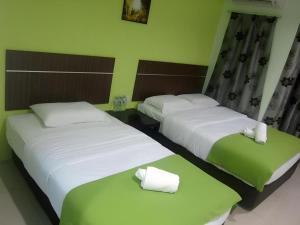 Dos camas en una habitación de hotel con sábanas blancas. en Eco Hotel Putra Kajang, en Sungai Chua