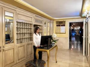 a woman standing at a table with a laptop at Hotel Alcyone in Venice