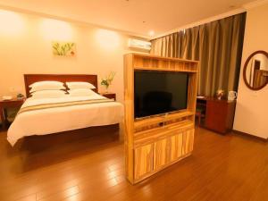 a bedroom with a bed and a large television at GreenTree Inn Hebei Tangshan North Station Nanhuandao Business Hotel in Fengrun