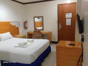 a bedroom with a bed and a desk and a television at Jeamco Royal Hotel - Pasig in Manila