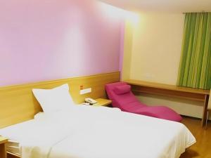 a hotel room with two beds and a pink chair at 7 Days Inn Jinggangshan Scenic Spot in Jinggangshanzonghekenzhichang +77 photos