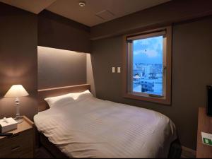 a bedroom with a white bed and a window at Ryuka Hotel Naha in Asato +120 photos