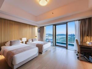 Huafa Executive Apartment Hotel Zhuhai في Cheoc Ca Chün: غرفة فندقية بسريرين ومكتب وبلكونة +249 صورة