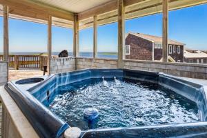 a hot tub on a porch with a view of the ocean at 8330 - Mariah in Avon