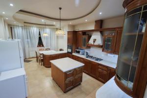 a large kitchen with wooden cabinets and a refrigerator at Marys Family Guest House in Yerevan