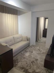 a living room with a white couch and a window at Deluxe Apartment 1 in Gnjilane