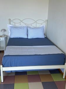 a bed with blue sheets and pillows in a room at AEGEAN view ! in Kavála