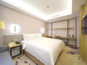 a bedroom with a large white bed and a desk at Lavande Hotel Yangzhou Railway Station Jiangwang RT-Mart in Yinjiahu