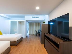 a hotel room with a bed and a flat screen tv at Hotel Holm Bangkok in Bangkok