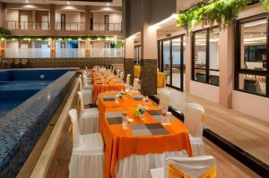a restaurant with orange tables and white chairs and a pool at Sumbawa Grand Hotel in Sumbawa Besar