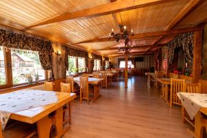 a restaurant with wooden tables and chairs and windows at Pensiunea Moeciu Casa Wiarusti in Moieciu de Sus