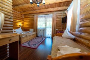a bedroom in a log cabin with two beds at Pensiunea Moeciu Casa Wiarusti in Moieciu de Sus