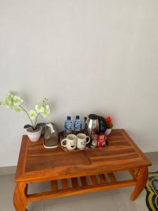 a wooden table with cups and drinks on it at The Angga House in Bangli