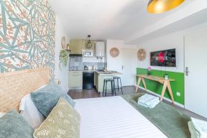 a living room with a bed and a kitchen at Hortensia Roanne centre-ville - Parking & Clim in Roanne