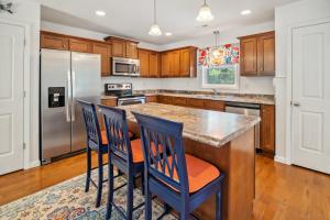 a kitchen with wooden cabinets and a island with two chairs at 5517 - Harbour Haven in Kill Devil Hills