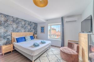 a bedroom with a bed and a chair and a window at Bleuet Roanne centre-ville -Parking & Clim in Roanne