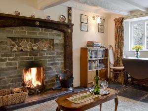 a living room with a fireplace and a table with a bottle of wine at Rowlandson Ground Cottage in High Yewdale