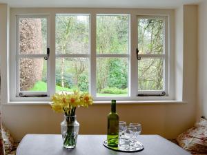 a table with a vase of flowers and a window at Rowlandson Ground Cottage in High Yewdale
