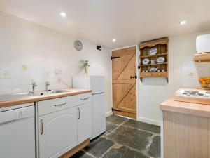a kitchen with a sink and a refrigerator at Rowlandson Ground Cottage in High Yewdale