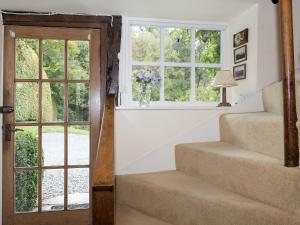 a stairway with a vase of flowers in a window at Rowlandson Ground Cottage in High Yewdale +9 photos