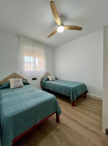 a bedroom with two beds and a ceiling fan at ÁTICO Paraíso Beach con piscina privada in Vera +55 photos