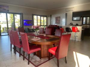 a dining room with a wooden table and red chairs at Peaceful picturesque Pecanwood in Hartbeespoort
