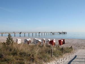 a beach with chairs and a pier in the water at Haffblick Whg Ha16 in Boltenhagen