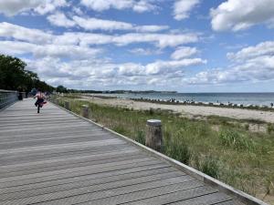 a woman walking down a boardwalk on the beach at Haffblick Whg Ha16 in Boltenhagen +17 photos