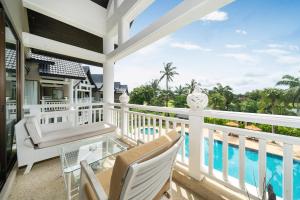 un balcon avec une table et des chaises et une piscine dans l'établissement Stylish Thai 2BR Condo Pool & Golf with Balcony, à Laguna Phuket