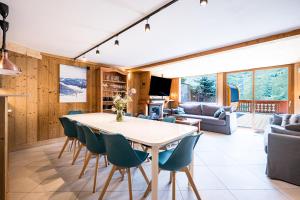 Les BruyèresにあるChalet Gabrielle Luxe ski aux piedsのテーブルと椅子のあるキッチンとリビングルーム
