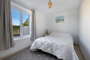 a white bedroom with a bed and a window at Maison à 50m de la mer, 4 adultes et 2 enfants in La Richemondière