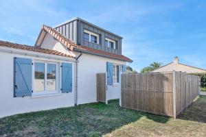 a white house with blue doors and a fence at Maison à 50m de la mer, 4 adultes et 2 enfants in La Richemondière