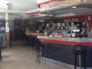 un bar en un restaurante con taburetes negros en Hostal Salones Victoria, en Santa Marina del Rey