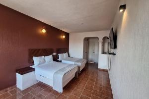 a hotel room with two beds and a television at Capital O Hotel Rolovi Cancún in Cancún