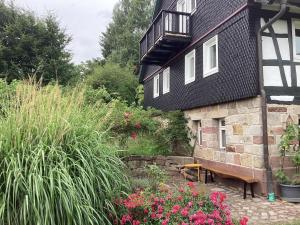 una casa con un banco y flores delante de ella en Ferienhaus Rhönmantisch - Landleben und Stille, en Brembach