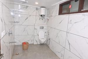 La salle de bains est pourvue de toilettes et de murs en marbre. dans l'établissement Hotel Golden By Admire Stay, à Jāmb