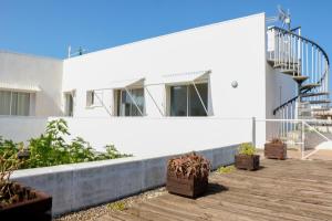 a white house with potted plants on a wooden deck at Villa Casa Bianca Beachfront Villeroy in Sète