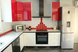 a kitchen with red cabinets and a white refrigerator at Villa Casa Bianca Beachfront Villeroy in Sète