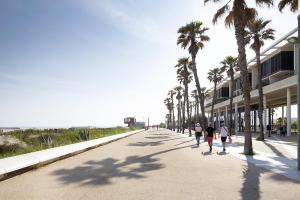 three people walking down a street with palm trees at Villa Casa Bianca Beachfront Villeroy in Sète +8 photos