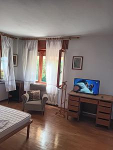 a living room with a tv on a dresser and a couch at Appartamento Dolomiti in Feltre