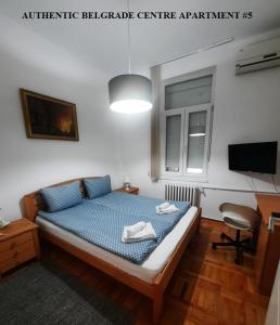 Authentic Belgrade Centre - New Year 2026 - Suites and large Apartments for Groups - Up to 63 Guests in one Building في بلغراد: غرفة نوم بسرير وملاءات زرقاء وتلفزيون