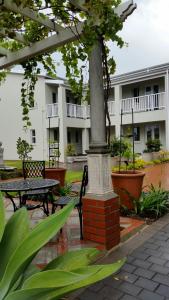 un poste en un patio con mesa y bancos en Bright on 5th Guest house en Port Elizabeth