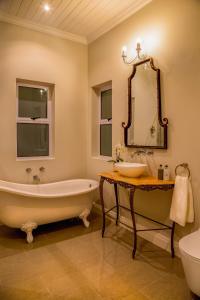 y baño con bañera, lavabo y espejo. en Bright on 5th Guest house en Port Elizabeth