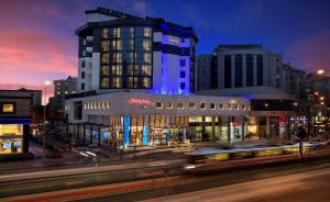 a building on a city street at night with a bus at Hampton By Hilton Gaziantep in Gaziantep