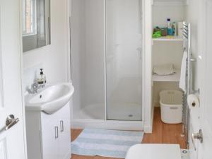 a white bathroom with a shower and a sink at Blackberry Lodge in Ripon