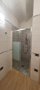 een badkamer met een douche met een glazen deur bij Residenza Tre Archi in Sìnnai