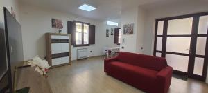een woonkamer met een rode bank en een keuken bij Residenza Tre Archi in Sìnnai