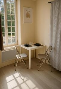 une pièce avec une table et deux chaises et une fenêtre dans l'établissement Appartement lumineux proche Abbaye & Centre de Caen, à Caen