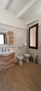 een badkamer met 2 wastafels, een toilet en een raam bij Residenza Tre Archi in Sìnnai